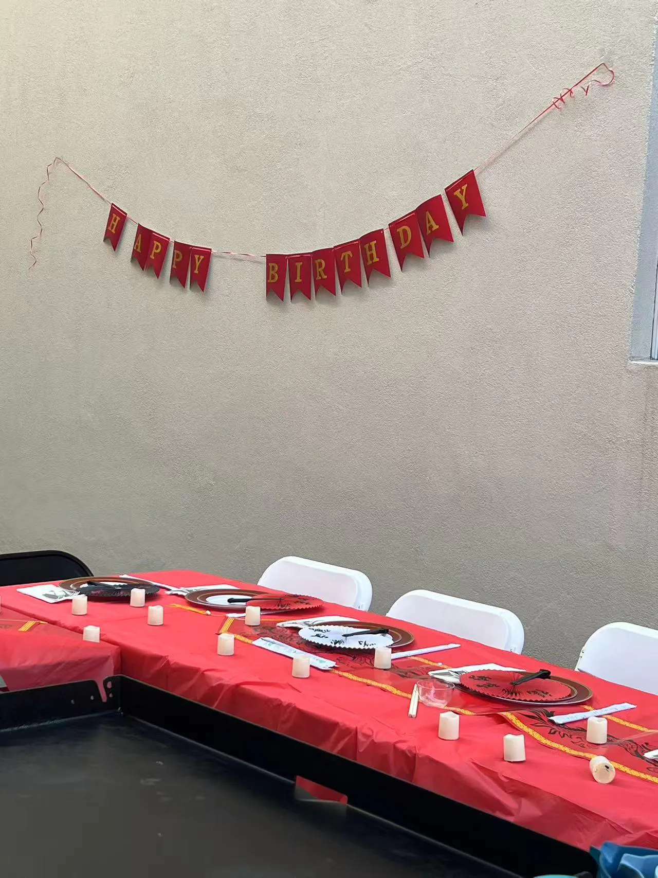 Red "Happy Birthday" banner above red tablecloth with party place settings