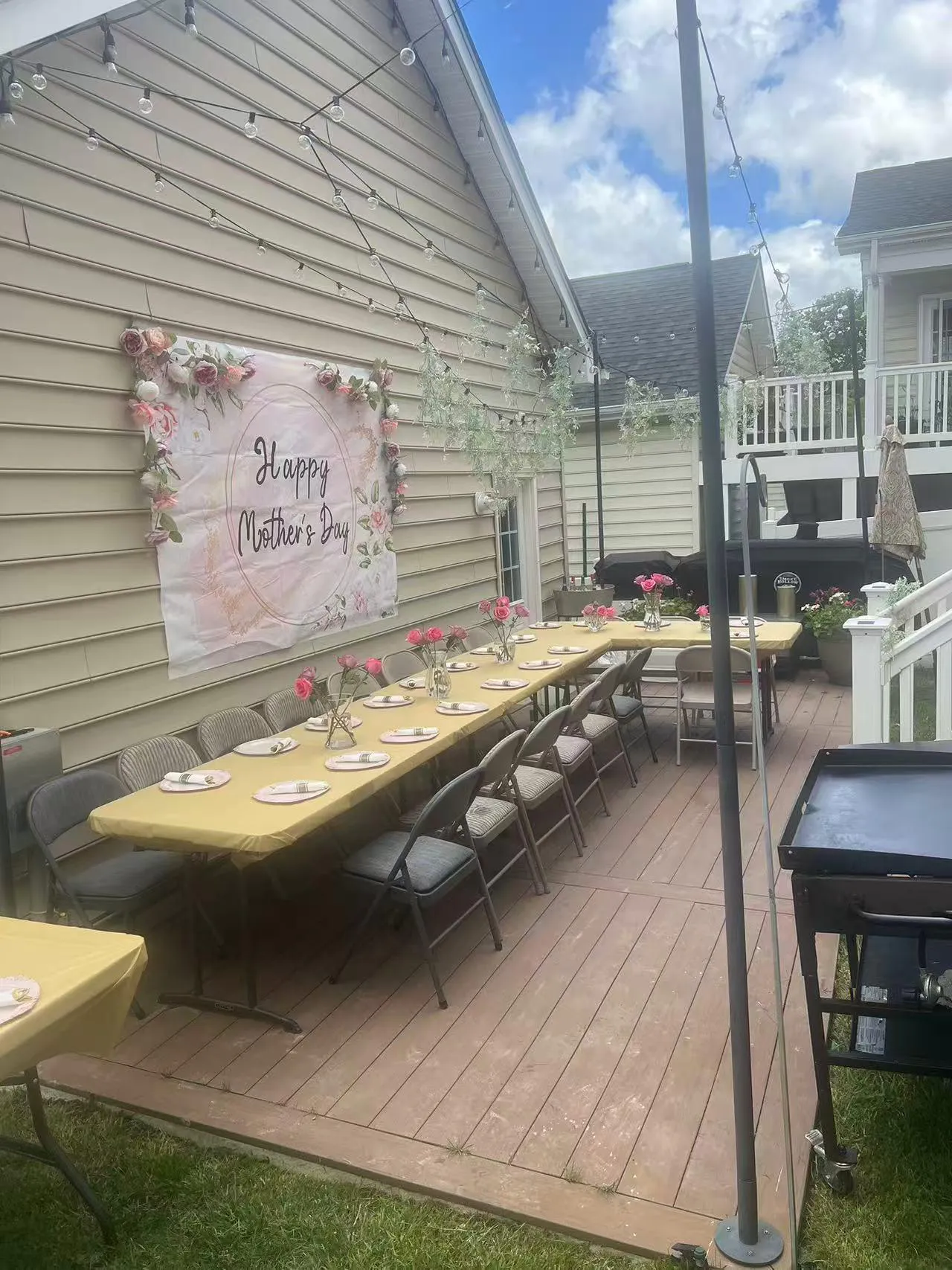 Mother's Day patio setup with "Happy Mother's Day" banner, yellow tables, string lights