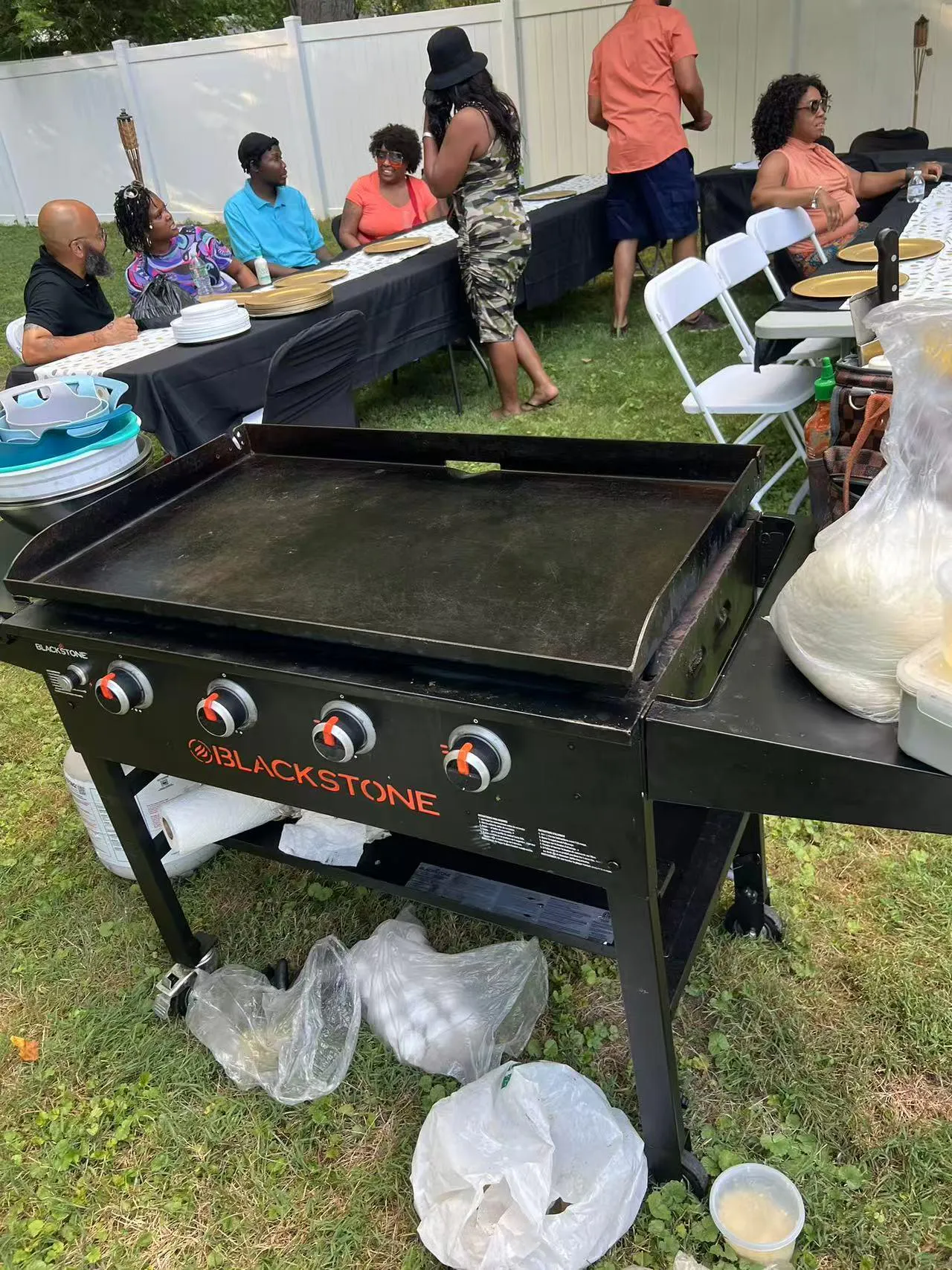 Blackstone 4-burner griddle at backyard gathering with guests seated at tables